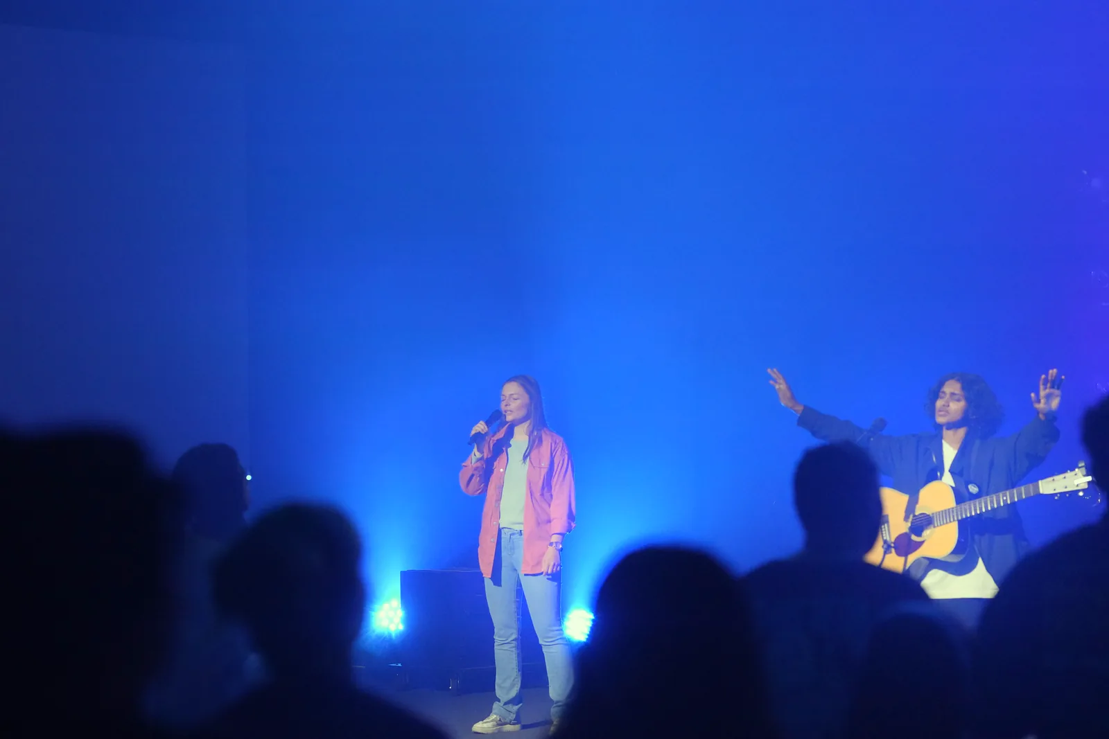 A singer beside a guitarist with raised hands during worship at Hue.Church on October 18, 2026